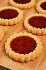 Raspberry jam tarts on wooden board 