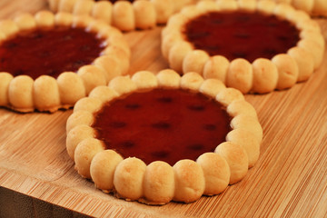 Raspberry jam tarts on wooden board 