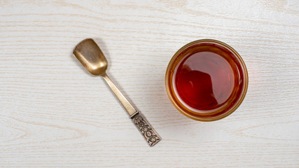 Top view of a Cup of tea with a Cup of Nickel silver teaspoon on a light wooden table top