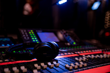 Headphones lying on an advances mixing console in dim lighting in an event venue