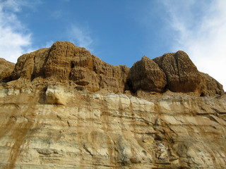 Eroded sandstone cliff peaks above sandstone striations along beach in Torrey Pines state park in San Diego County with blue sky background 