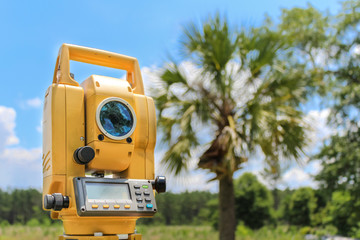 Electronic distance measurement device used for land surveying with blue sky and cloud background and a palmetto tree