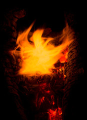 Fototapeta na wymiar Close up of flames dancing in a fire above red embers in a campfire