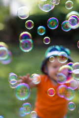 small boy playing in the background behind colorful bubbles floating in the air