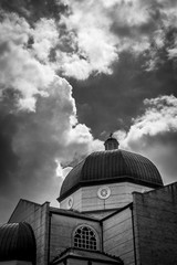 Sunshine through clouds on greek orthodox church building and dome peaked with cross