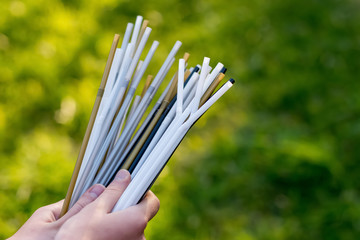 Hand holding plastic straws on green grass background. Plastic pollution, environmental waste. Plastic pollution, environmental waste. Say no to plastic straws. Save our green planet