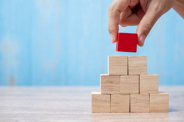 Businessman hand placing or pulling Red wooden block on the building. Business planning, Risk Management, Solution, strategy, different and Unique Concepts