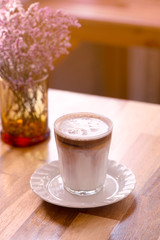 cup of coffee with cream on wooden background