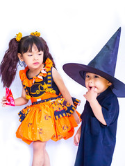 Asian children girl in pumpkin dress costume for Halloween decoration with pumpkins with brother black shirt in white background