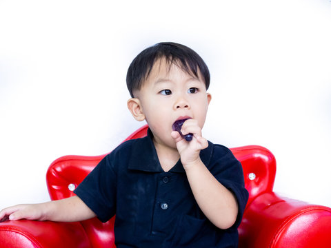 ฺBaby boy in black shait is eating delicious jelly