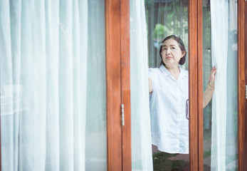 Senior healthy concept,Mature Asian elderly woman having migraine and looking something near window...