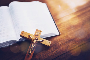 Obraz premium Close up of Jesus's crucifix over bible on wooden table background, copy space