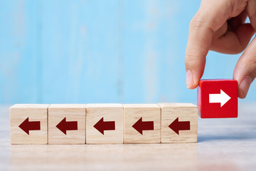 Businessman hand placing or pulling Red block with different direction of arrow on table background. Business Growth, Improvement, strategy, Successful, different and Unique Concepts