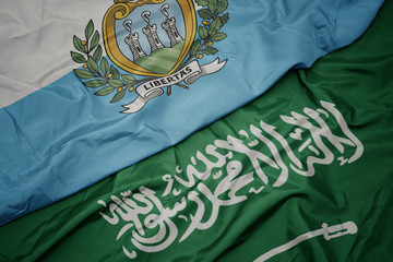 waving colorful flag of saudi arabia and national flag of san marino.