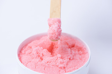 Pink sugar scrub with the smell of strawberries for the depilation process on a white background