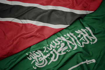 waving colorful flag of saudi arabia and national flag of trinidad and tobago.