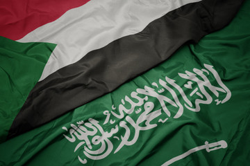 waving colorful flag of saudi arabia and national flag of sudan