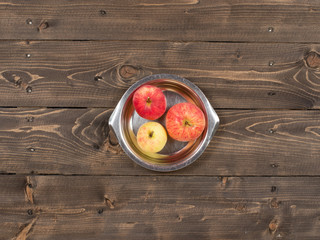 Three apples in a stainless plate on a wooden rustic table top view