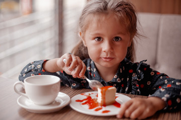 Little girl eating cake in cafe