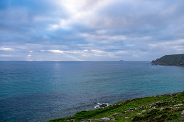 Grass shore overlooking the sun rays shinning through the clouds in England, UK.
