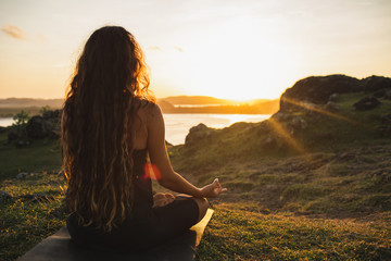Woman meditating yoga alone at sunrise mountains. View from behind. Travel Lifestyle spiritual relaxation concept. Harmony with nature.