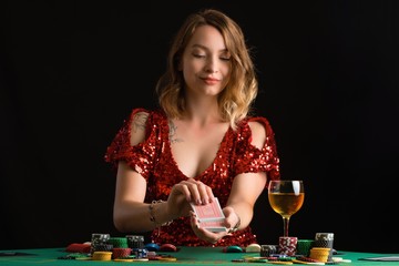 A young girl in a red evening dress plays poker in a casino. Success gaming business