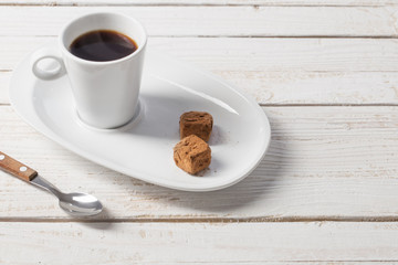 cup of coffee with chocolate candy on white old wooden table