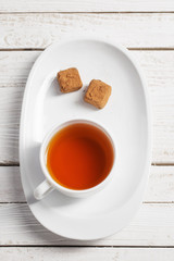 cup of tea with chocolate candy on wooden table