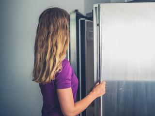 Fototapeta na wymiar Young woman opening her fridge