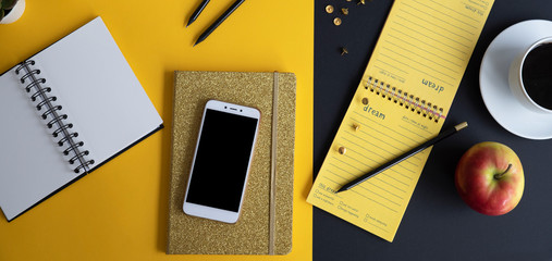 Flat lay office desktop in modern design and colors. Gold notebook, smartphone, pencil, cup of coffee, apple and organizer with mock up. Panoramic banner with top view.
