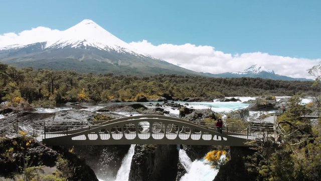 Aerial view of the tourist contemplating the landscape from the bridge on cascades in Petrohue at the slopes of the volcano Osorno, Chile. 4k