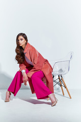 High fashion portrait of young elegant woman. Coral coat, magenta pants, white blouse. - 290659329