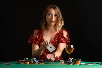 A young girl in a red evening dress plays poker in a casino. on a black background with space for design