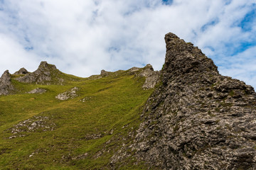 Looking up to alien-like rocky hills covered in a green vegetation on partially cloudy day in England, UK.