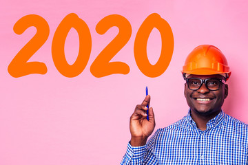 African American man with helmet hardhat pointing finger at pink wall with drawing new year 2020...