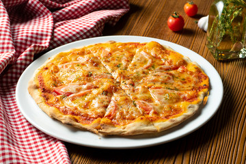 Fresh homemade Margarita pizza on a wooden background in composition with a red cloth and olive oil. Italian Cuisine. Selective focus on center of pizza