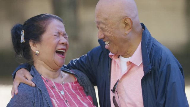 Portrait of senior couple laughing as they talk with each other, in slow motion