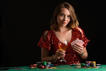 A young girl in a red evening dress plays poker in a casino. on a black background with space for design