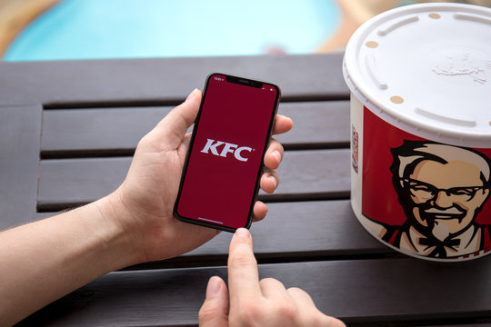 Man hands holding iPhone X with app Kentucky Fried Chicken