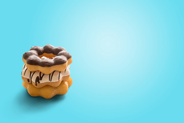 Three stacked donuts on pastel blue background.