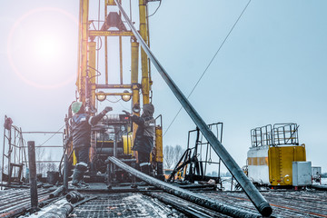 Offshore oil rig worker prepare tool and equipment for perforation oil and gas well at wellhead platform. Making up a drill pipe connection. A view for drill pipe connection from between the stands