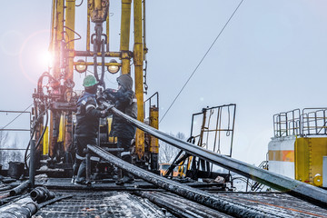 Offshore oil rig worker prepare tool and equipment for perforation oil and gas well at wellhead platform. Making up a drill pipe connection. A view for drill pipe connection from between the stands