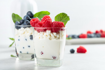 Cottage cheese with cream, raspberry and blueberry garnished with fresh mint.