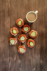 Small tasty sandwiches on an old wooden table with a cup of coffee. Top down view.