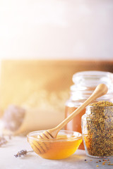 Bee pollen granules, honey jar with wooden dropper, honeycomb on grey backdrop. Copy space. Autumn harvest concept