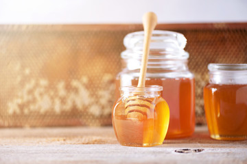 Honey dripping from wooden honey spoon in jar on grey background. Copy space. Autumn harvest concept.