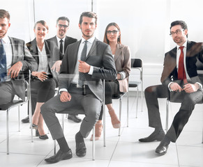 Man and women sitting on chairs in row