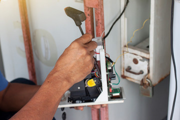The hands of a mechanic holding a screwdriver to fix the vending machine.