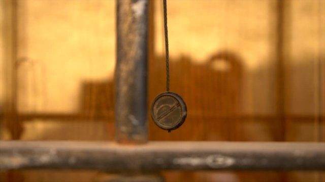 Curtain rope moving as a pendulum under a soft wind. In front of a warm orange window