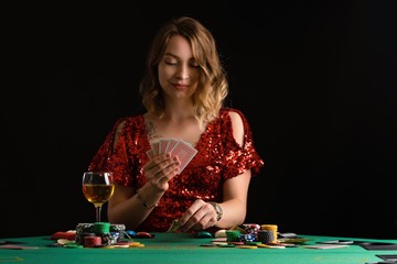 A young girl in a red evening dress plays poker in a casino. on a black background with space for design